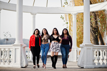 Group of four happy and pretty latino girls from Ecuador posed at street against ancient arch.