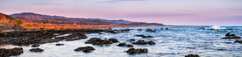Panoramic view of the dramatic Pacific Ocean coastline at sunset, during low tide, Santa Cruz mountains in the background; San Francisco bay area, California