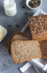 Sliced whole wheat bread baked with seeds and butter on wooden cutting board. Simple breakfast.