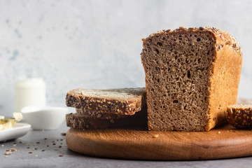 Sliced whole wheat bread baked with seeds and butter on wooden cutting board. Simple breakfast.