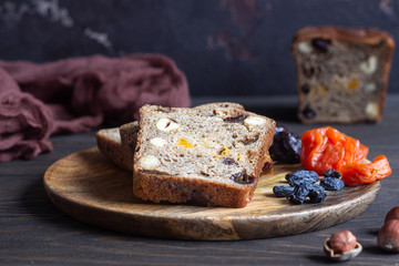 Bread with dried fruits and nuts on old wooden table. Homemade festive whole grain bread with dried fruits and nuts. Rustic style.