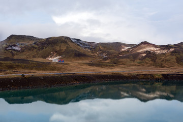 view of house near the lake in abandoned landscape in Iceland, in the background of a snowy mountain