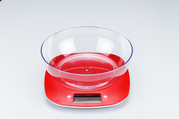 An electronic scale with a measuring cup on white background.