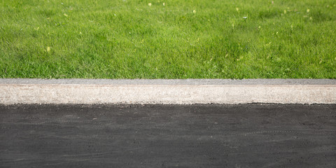 Green Grass Grows Near Black Asphalt, Separated By Concrete Border. Road And Lawn Divided By...