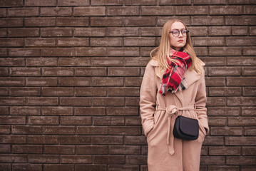 Blonde young woman in eye glasses . Optics style. wearing a coat and scarf outside