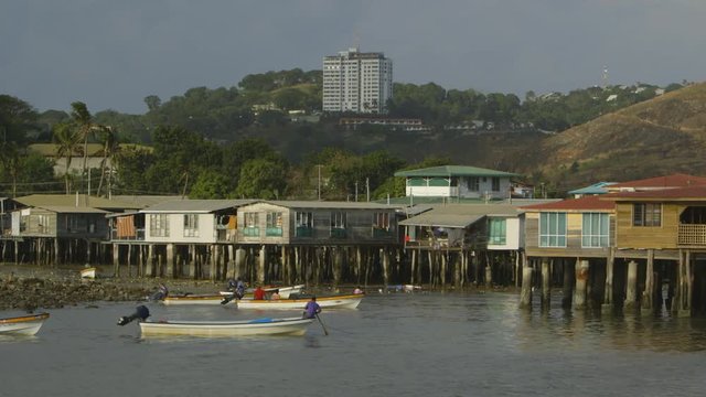 Medium still shot of motor canoe owners at Koki village arriving  and slowly arranging their boats  in position close to their floating houses, Port Moresby