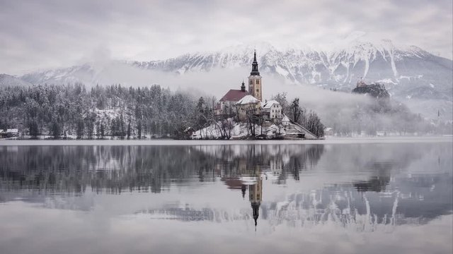 Winter time-lapse footage of famous Church Island at Lake Bled with Castle and Alps in the background