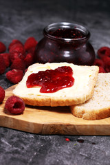 Toast bread with homemade raspberry jam or marmalade on rustic table served with butter for breakfast or brunch
