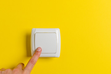 finger press light switch on a bright yellow background