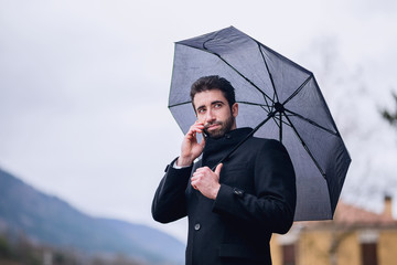 Man under umbrella phoning in the street