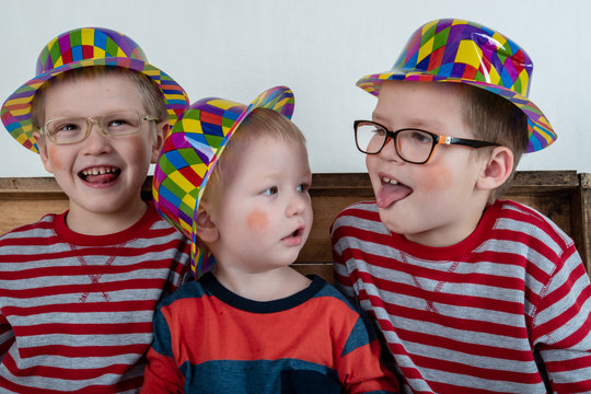 Funny clown children dressed up in costumes and represent the circus. The child is playing at home. The hat is a bowler and a yellow patch on the nose. 1 April. concept of a fool's day. Copy space.