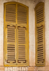 Wooden weathered vintage grunge yellow window shutters of old house corner wall facade closeup