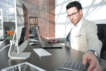 behind the glass.serious businessman with calculator sitting at his Desk