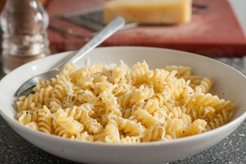 A bowl of fusilli pasta served with butter and grated cheese