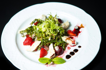 Strawberry tomato salad with feta cheese, olive oil on black background