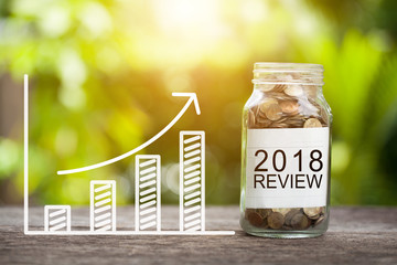 2018 review word with coin in glass jar and graph up. financial concept