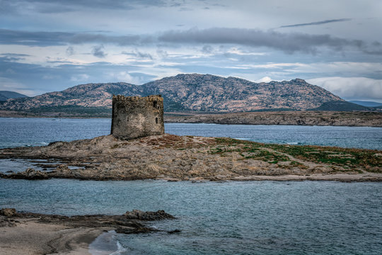 The Aragonese tower, built in 1578, called Pelosa Tower and, on a cloudy morning at Spiaggia della Pelosetta Beach and the Golfo dell'Asinara, Sardinia, Italy