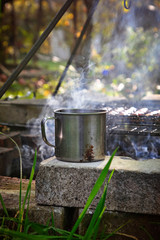 Iron mug with hot drink near fire