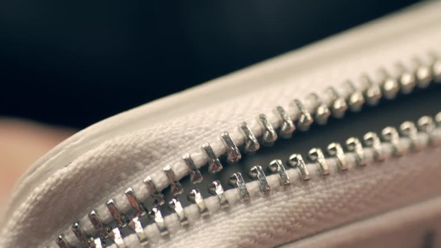 Macro shot of opening white wallet, unzipping zipper