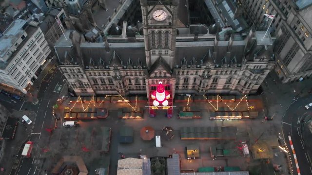 4K footage of a Drone flying over Manchester Christmas Markets during the early cold mornings Albert Square Town Hall and above Zippy Santa Claus Statue Panning upwards while flying down.
