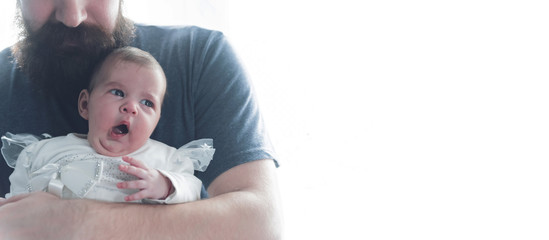 Baby girl yawning in her father's arms