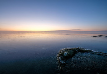 moss and ice on a lake in the foreground with sunrise in the background