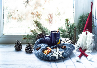 Blue cup with tea and leprechaun on the background of window with  winter pattern. The concept of...