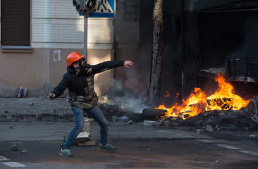 Street protester with a burning Molotov cocktail against a fire