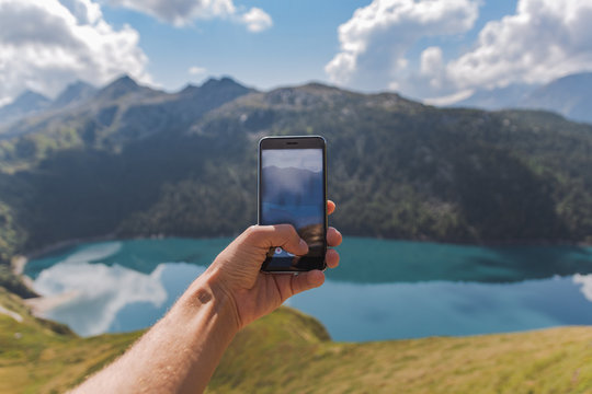 young man hand holding a smartphone and take a picture of an astonishing panorama