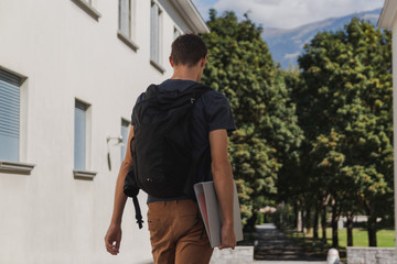 young man with backpack walking to school after summer holidays