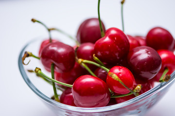The glass bowl filled  with ripe cherries