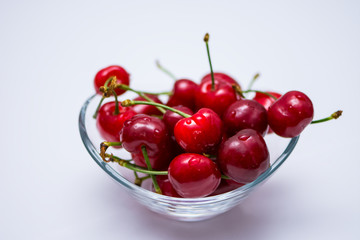 Obraz na płótnie Canvas The glass bowl filled with ripe cherries