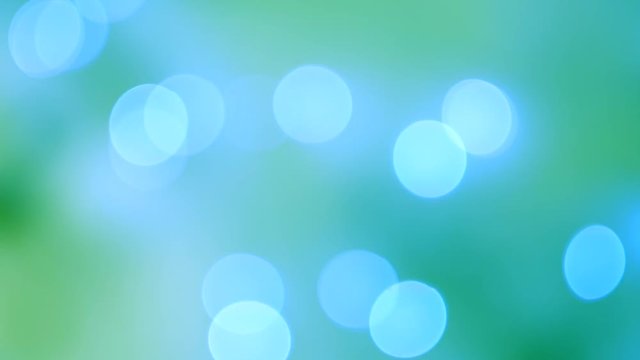 Abstract blue bokeh lights on blurred turquoise background. Bright bokeh effect on smooth defocused green background. Holiday spirit. 