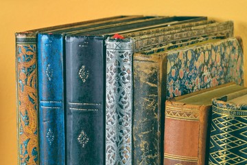 Cultural heritage. Antique books on old wooden shelf. Old books on yellow background. Close up