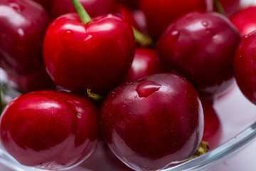 The glass bowl filled  with ripe cherries