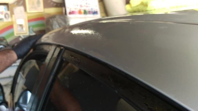 A close up of a man applying a polish to the side of a car.