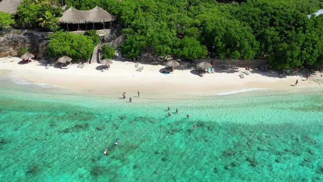 A Small Group of People Enjoying a Perfect Day on a Pristine Tropical Beach in Cura&radic;&szlig;ao in the Caribbean Islands, Aerial Approach and Tilt Down Shot