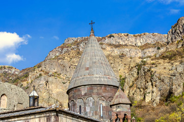 Fototapeta premium View of all domes with crosses and a cave church with carved khachkars on the walls, in the Geghard monastery in Armenia