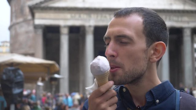 Male Backpacker Eating Gelato In Front Of Famous Landmark In Rome.