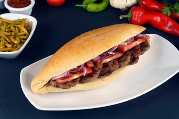 Delicious Turkish Meatballs Sandwich, Kofte Ekmek. Ingredients with bread crumbs, butter, sliced onion, parsley, tomato, pickles and seasoning spices. Hamburger serving on wood table background. 