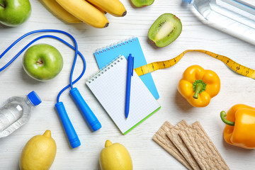 Flat lay composition with notebooks, healthy food and jumping rope on wooden background. Weight...