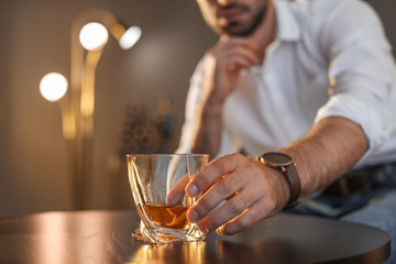 Man sitting at table with glass of whiskey, closeup. Space for text