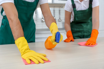 Team of janitors cleaning table in kitchen, closeup