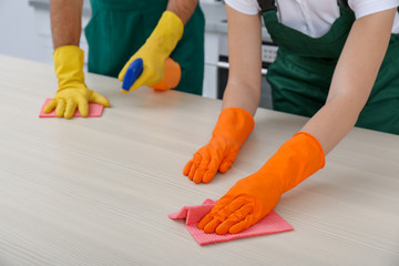 Team of janitors cleaning table in kitchen, closeup
