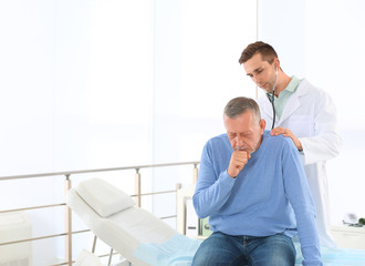 Doctor examining mature patient with stethoscope in hospital. Space for text