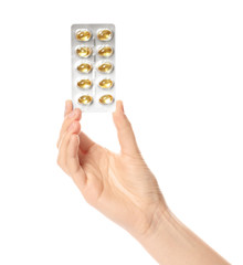 Woman holding pills in blister pack on white background, closeup