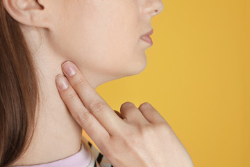 Young woman checking pulse against color background, closeup. Space for text