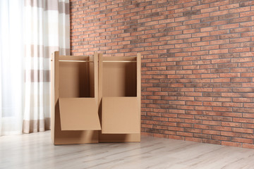 Empty cardboard wardrobe boxes against brick wall. Space for text