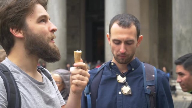 Male Backpackers Eating Ice Cream Cones On A Sunny Day In Rome.