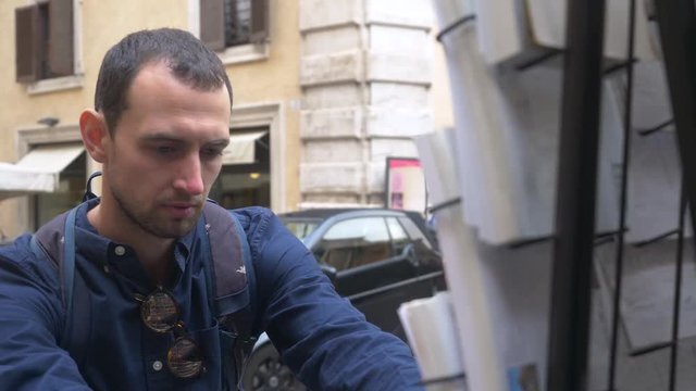 Male Tourist Choosing Postcards From A Street Vendor In Rome.